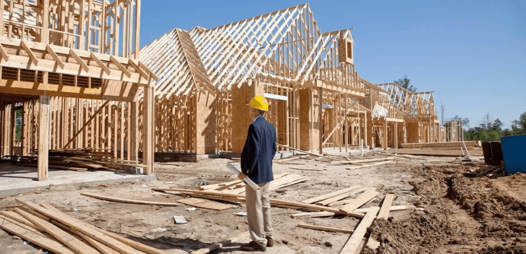 Builder in front of the frame of the completed house